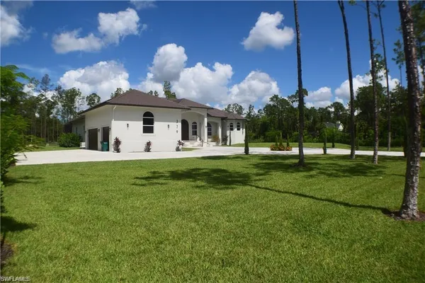 a front view of a house with garden and trees