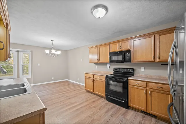 a kitchen with stainless steel appliances granite countertop a stove top oven a sink dishwasher a microwave oven and a refrigerator with wooden floor