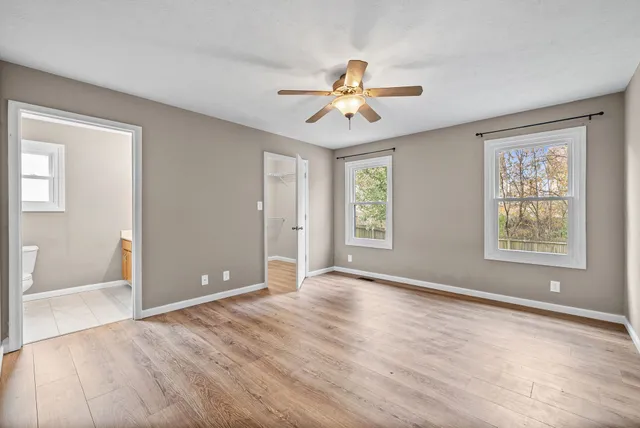a view of an empty room with window and wooden floor