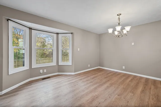 a view of wooden floor and a chandelier in big room