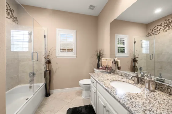 a bathroom with a granite countertop sink a mirror a bathtub and toilet