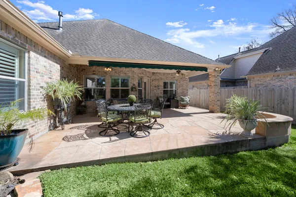 a view of a patio with table and chairs potted plants and floor to ceiling window