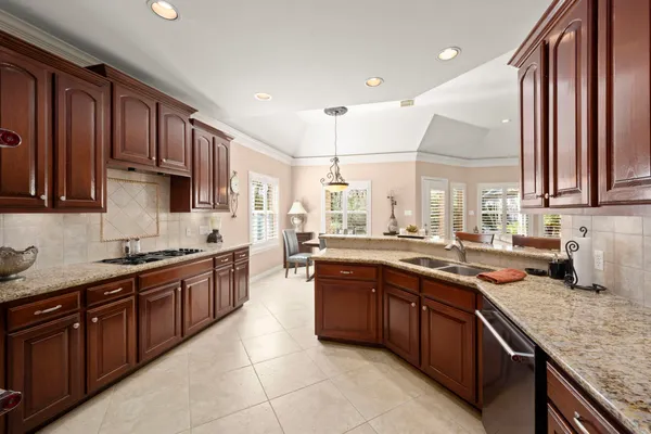 a kitchen with stainless steel appliances granite countertop wooden cabinets a sink and dishwasher a stove top oven with wooden floor