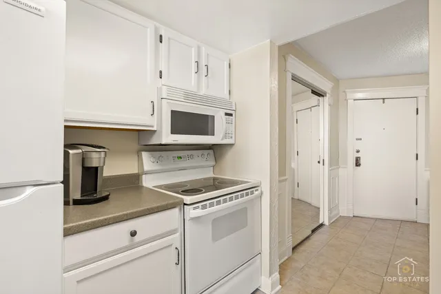 a kitchen with white cabinets and appliances