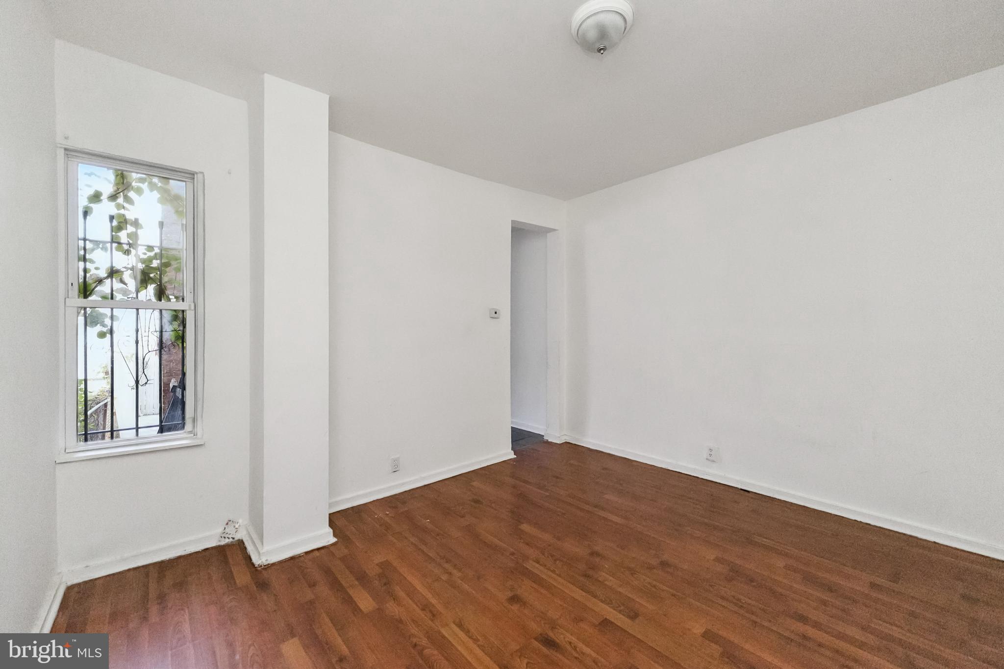 1828 Walbrook Avenue Baltimore, MD 21217 - Photo 7 of 15 an empty room with wooden floor and windows