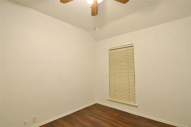 an empty room with wooden floor chandelier fan and windows