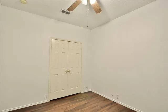 an empty room with wooden floor and ceiling fan
