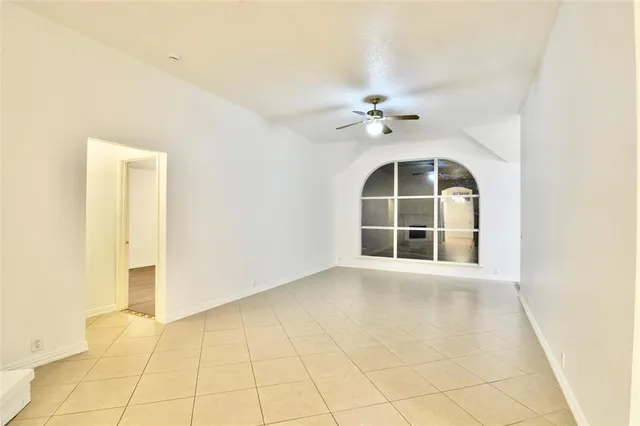 an empty room with windows and ceiling fan