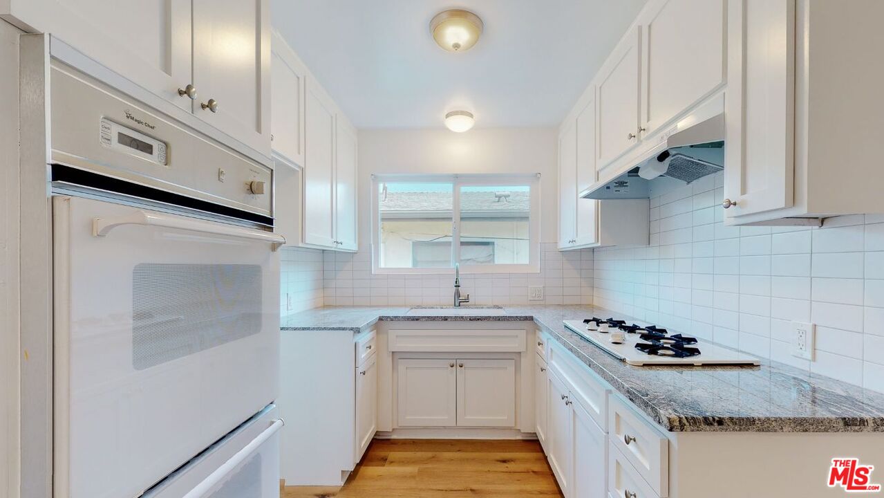 a kitchen with granite countertop a sink stove and cabinets