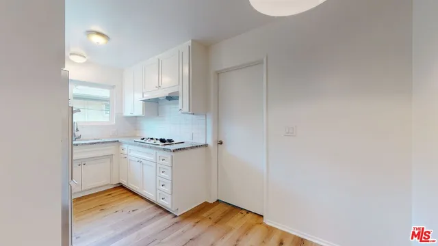 a kitchen with granite countertop white cabinets and a stove