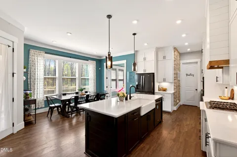 a living room with stainless steel appliances kitchen island granite countertop a sink and wooden floors