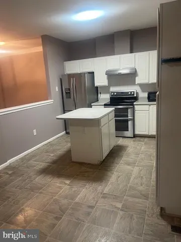 a kitchen with a sink a stove top oven and white cabinets