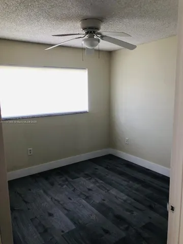 an empty room with a ceiling fan and wooden floor