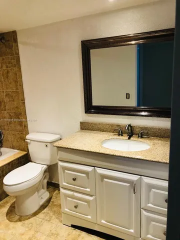 a bathroom with a granite countertop toilet sink and mirror