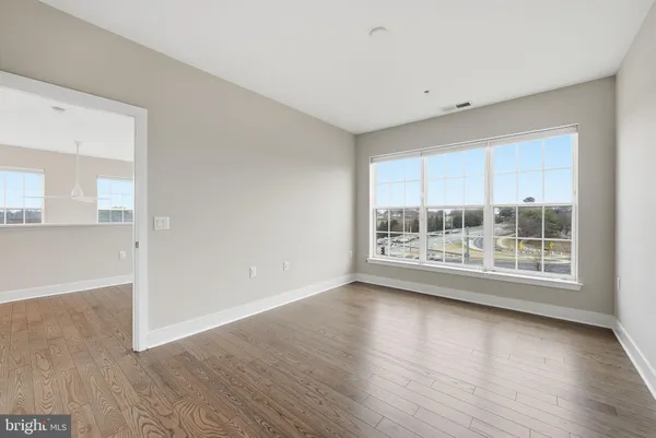 a view of an empty room with a window and wooden floor