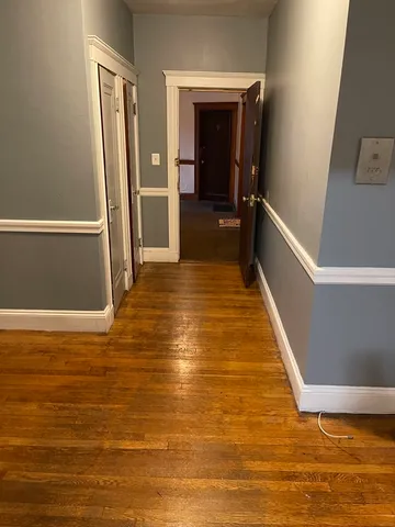 a view of a hallway with wooden floor and a room