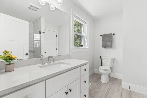 a bathroom with a sink toilet a mirror and a window