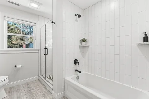 a bathroom with a bathtub a window and a shower