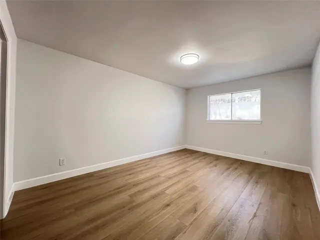 a view of an empty room with wooden floor and window