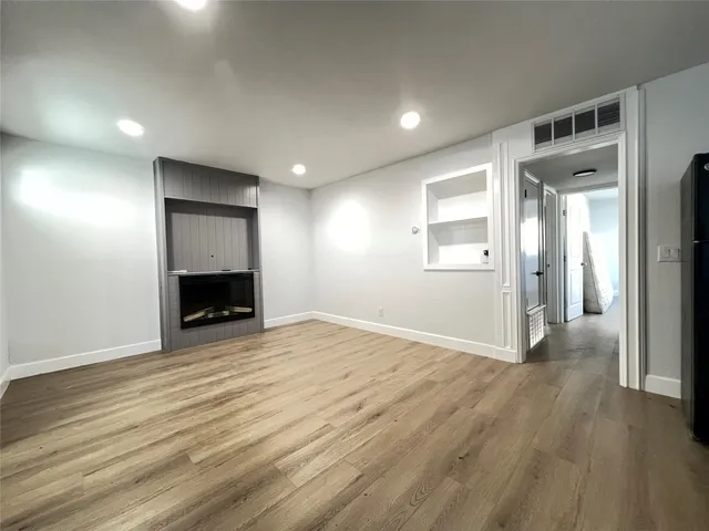 an empty room with wooden floor and a fireplace