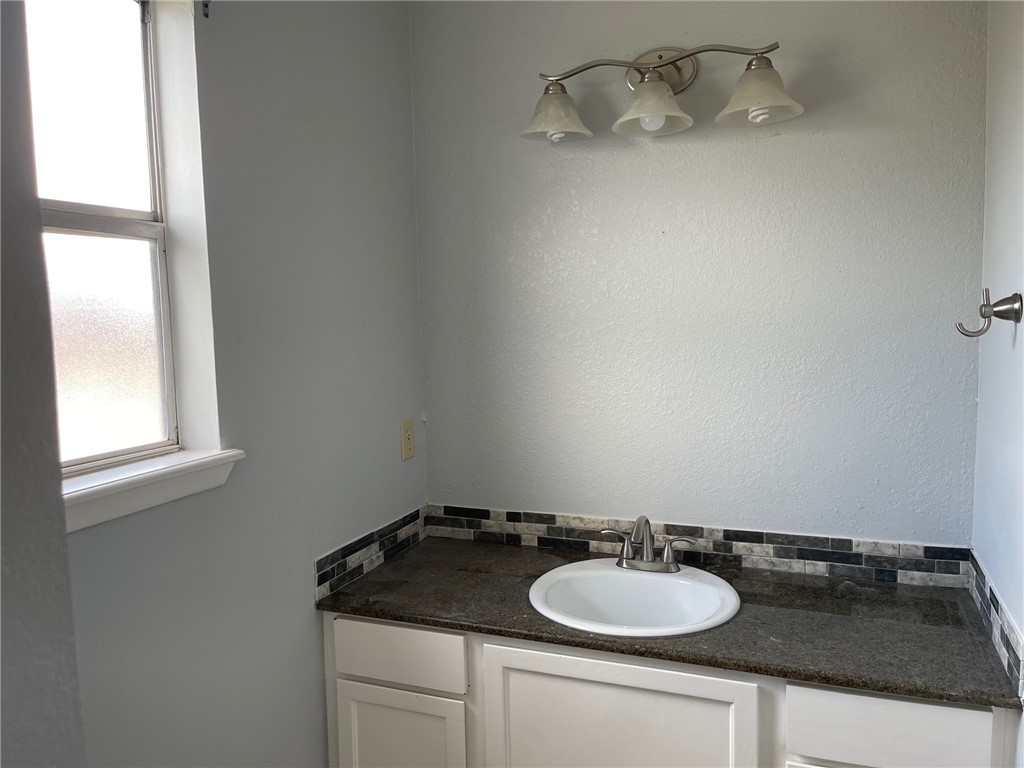 11605 Post Oak Circle, Unit 2 Corpus Christi, TX 78410 - Photo 3 of 7 a bathroom with a granite countertop sink and a mirror