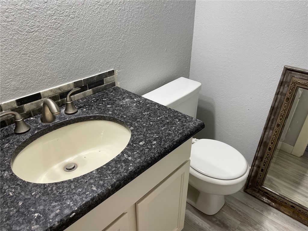 11605 Post Oak Circle, Unit 2 Corpus Christi, TX 78410 - Photo 4 of 7 a bathroom with a granite countertop toilet and a sink