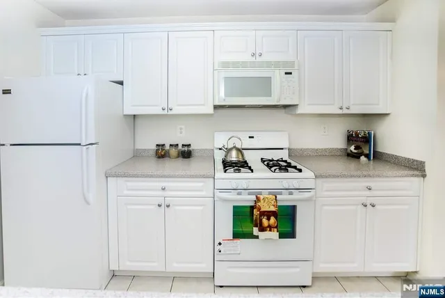 a kitchen with white cabinets and white appliances