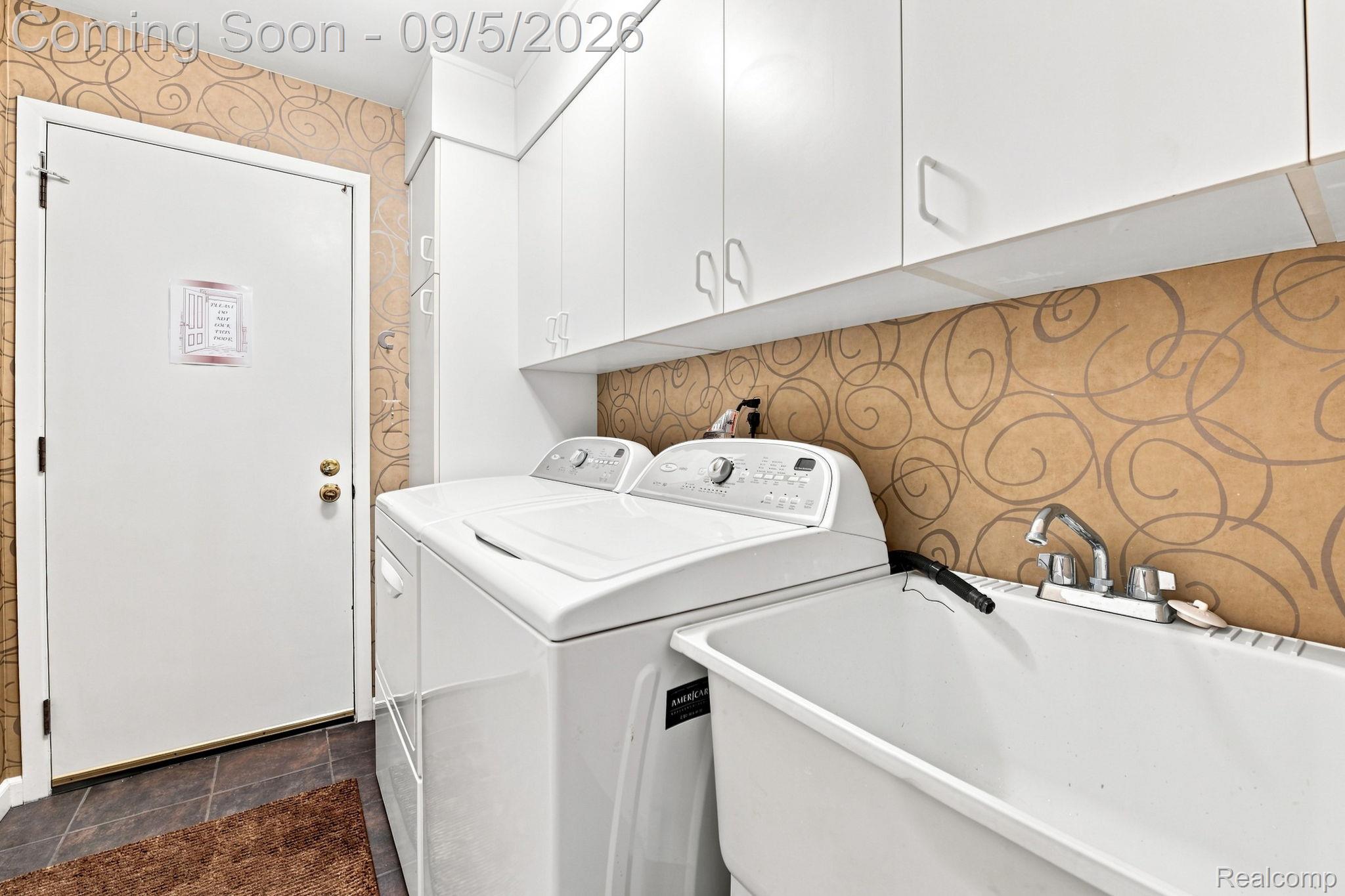 29690 Pine Ridge Circle Farmington, MI 48331 - Photo 22 of 32 White upper cabinetry, utility sink with chrome faucet, patterned wall covering, and dark tiled flooring