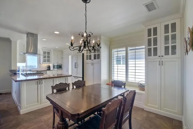 a dining room with stainless steel appliances granite countertop a dining table chairs and chandelier