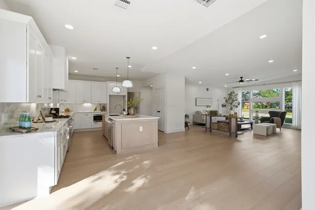 a large white kitchen with a large counter top furniture and a living room