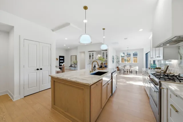 a large kitchen with stainless steel appliances a stove a sink dishwasher and a dining table with wooden floor