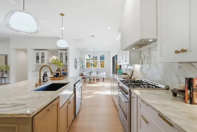 a kitchen with granite countertop a stove a sink a counter space and cabinets