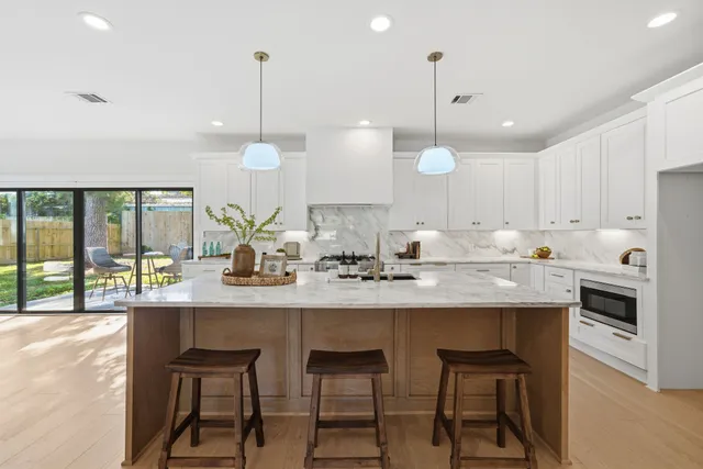 a kitchen with kitchen island granite countertop a sink a stove a dining table and chairs