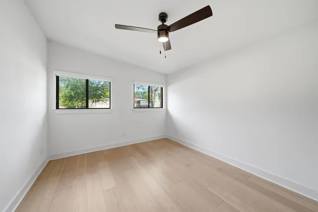 an empty room with windows and fan