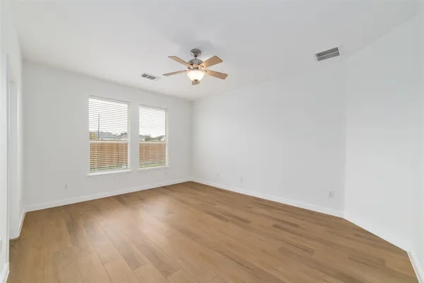 a view of an empty room with a window and wooden floor