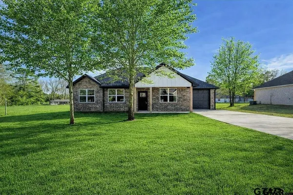a front view of a house with a yard and tree