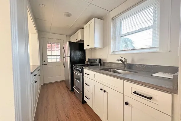 a kitchen with granite countertop a sink cabinets stainless steel appliances and a window