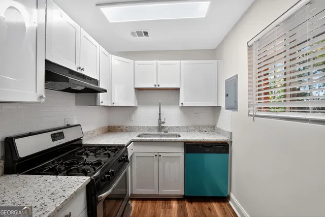 a kitchen with granite countertop a sink stove and cabinets