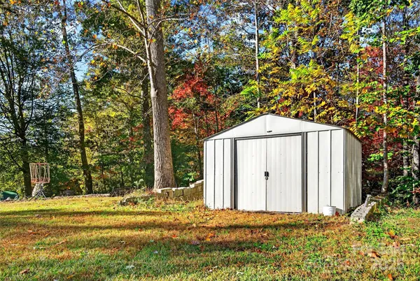 a view of a tiny house with large trees and wooden fence