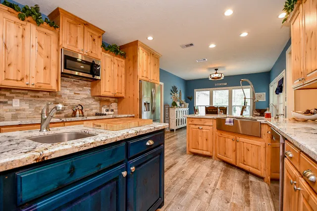 a large kitchen with granite countertop a sink and cabinets
