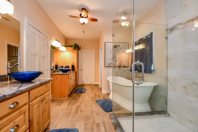 a spacious bathroom with stainless steel appliances a sink a mirror and shower