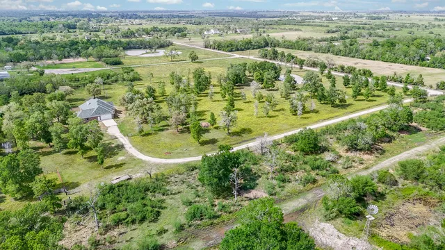 an aerial view of a residential houses with outdoor space and trees