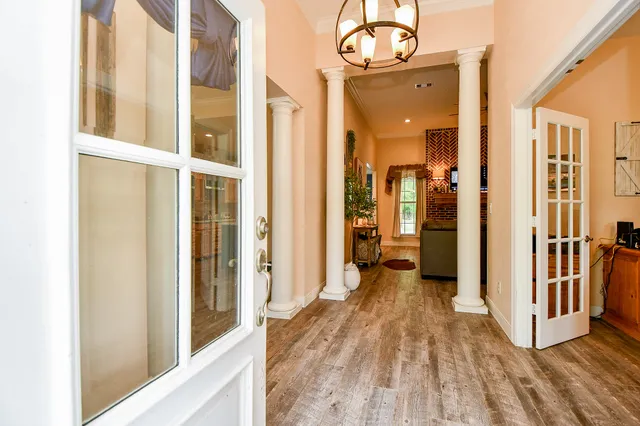 a view of a hallway with wooden floor and a bathroom