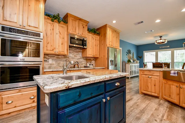 a kitchen with stainless steel appliances granite countertop a sink a stove and a microwave