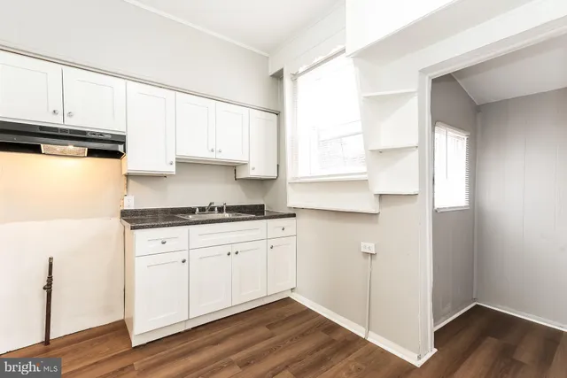 a kitchen with granite countertop white cabinets and a hard wood floor