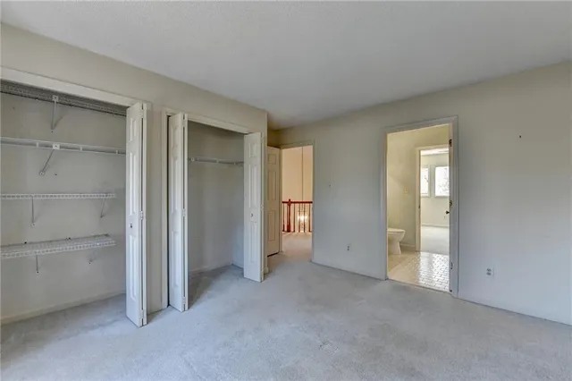 a front view of a building with large trees and cars parked