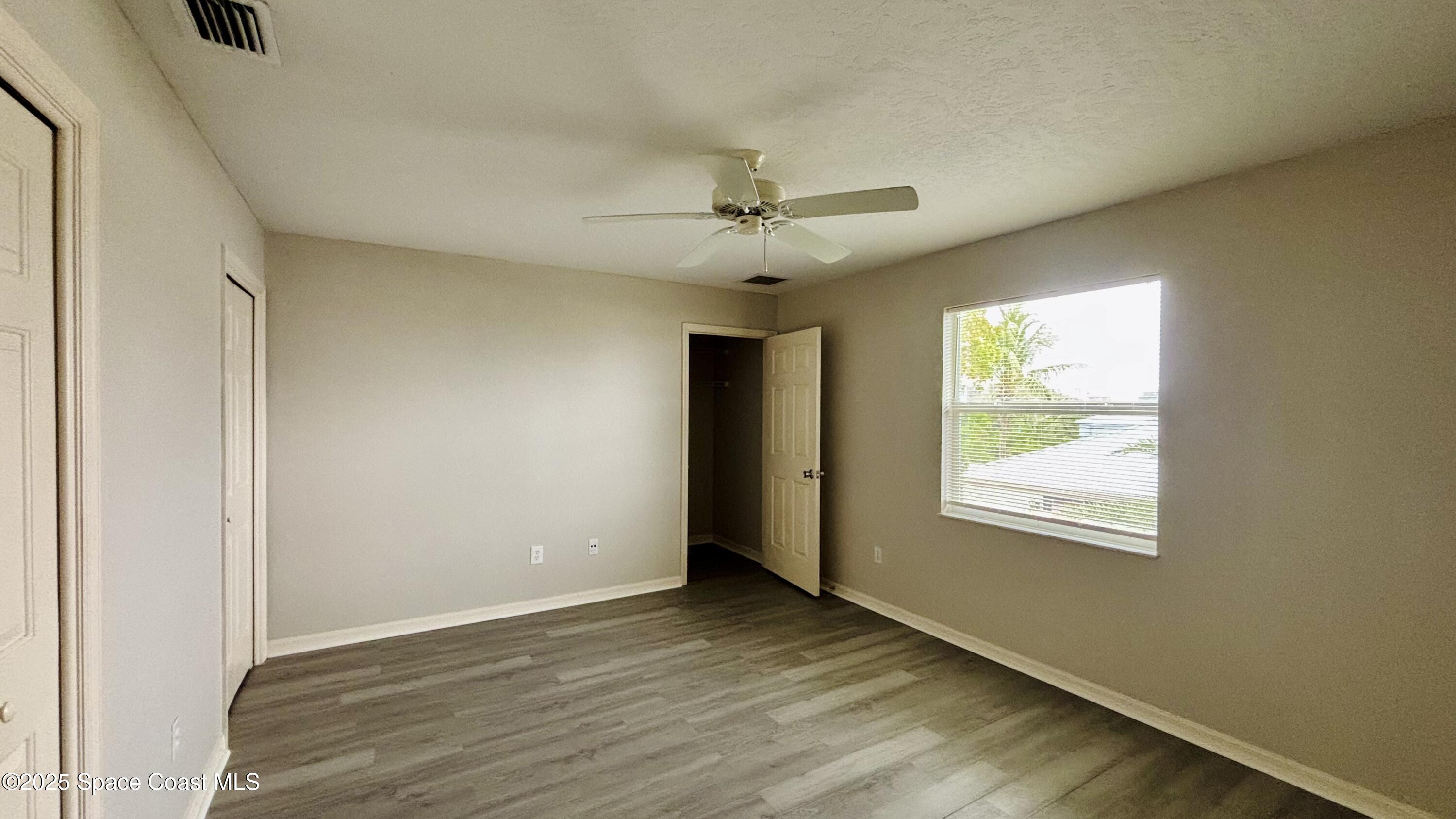 5508 Ambersand Place Grant-Valkaria, FL 32949 - Photo 17 of 30 an empty room with wooden floor ceiling fan and windows