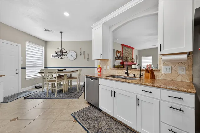 a kitchen with kitchen island granite countertop lots of white cabinets a sink and appliances
