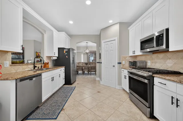 a large kitchen with stainless steel appliances granite countertop a stove a sink and a microwave
