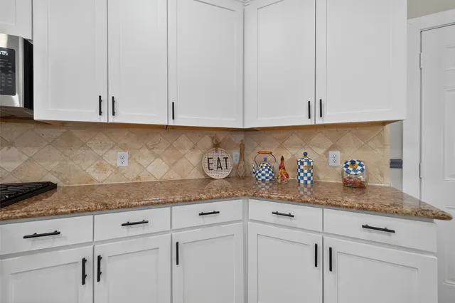 a kitchen with granite countertop white cabinets and a sink
